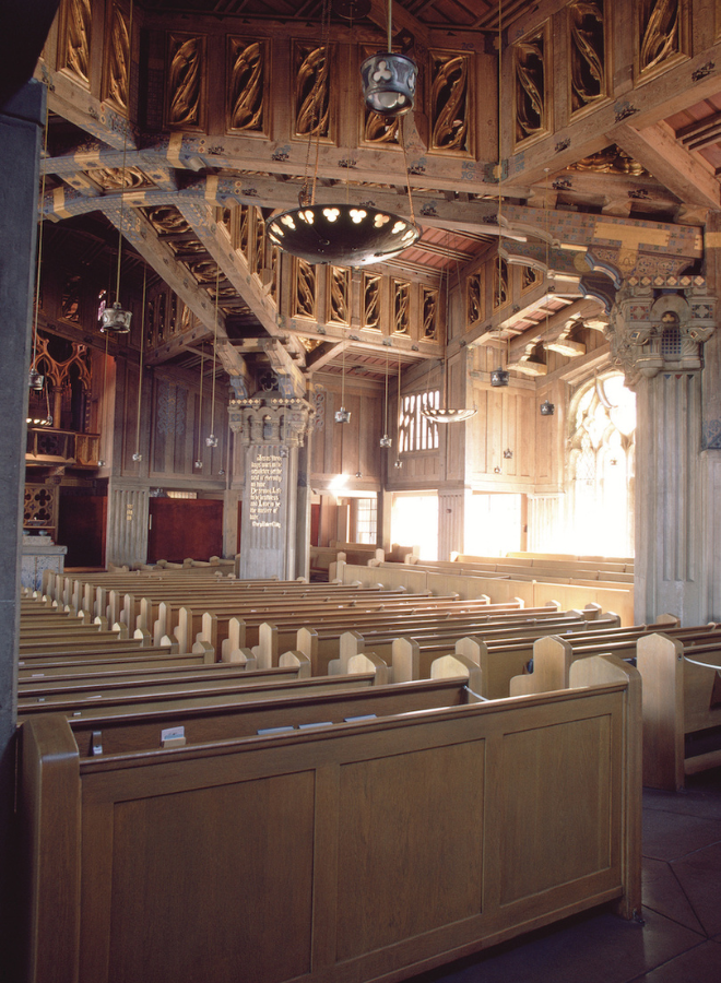 Inside of a church with pews, beams and a pulpit.