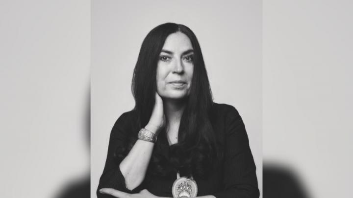 A black and white headshot of an Indigenous woman with dark hair wearing a black shirt