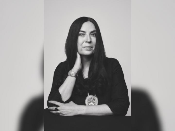 A black and white headshot of an Indigenous woman with dark hair wearing a black shirt