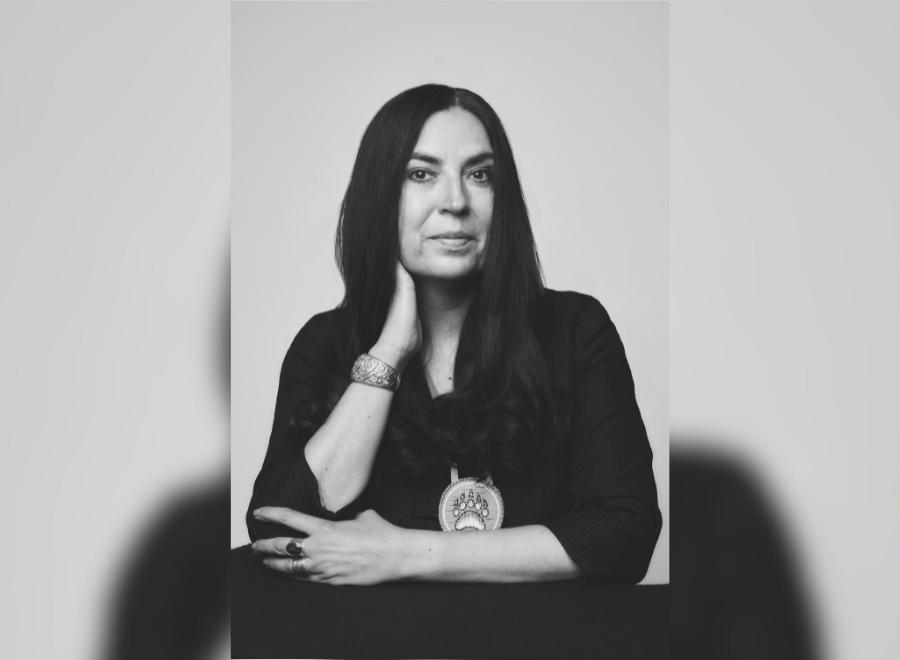 A black and white headshot of an Indigenous woman with dark hair wearing a black shirt