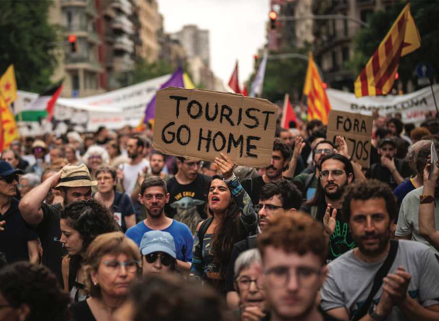 Protestors took to the streets of Barcelona. One woman holds a cardboard sign that says Tourist Go Home.