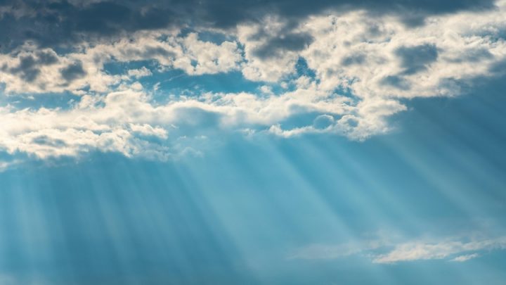 Rays of sunshine shine through clouds and a blue sky