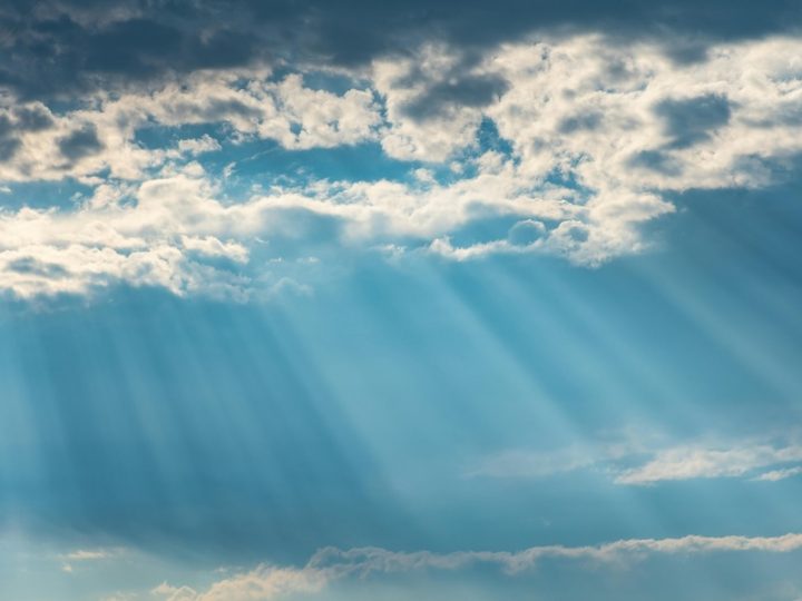 Rays of sunshine shine through clouds and a blue sky