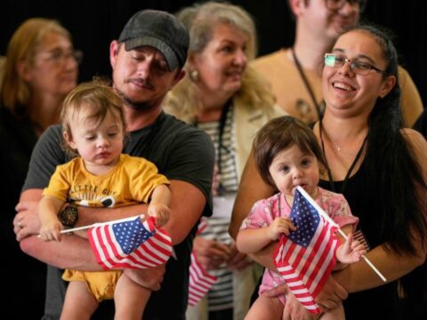 A man and a woman hold two toddlers, who holds American flags