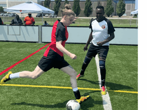 Emma Bellante, wearing a red and black jersey, kicks a soccer ball while a player in a white and black jersey defends during a match at the Canadian Street Soccer Association’s national tournament in Mississauga.