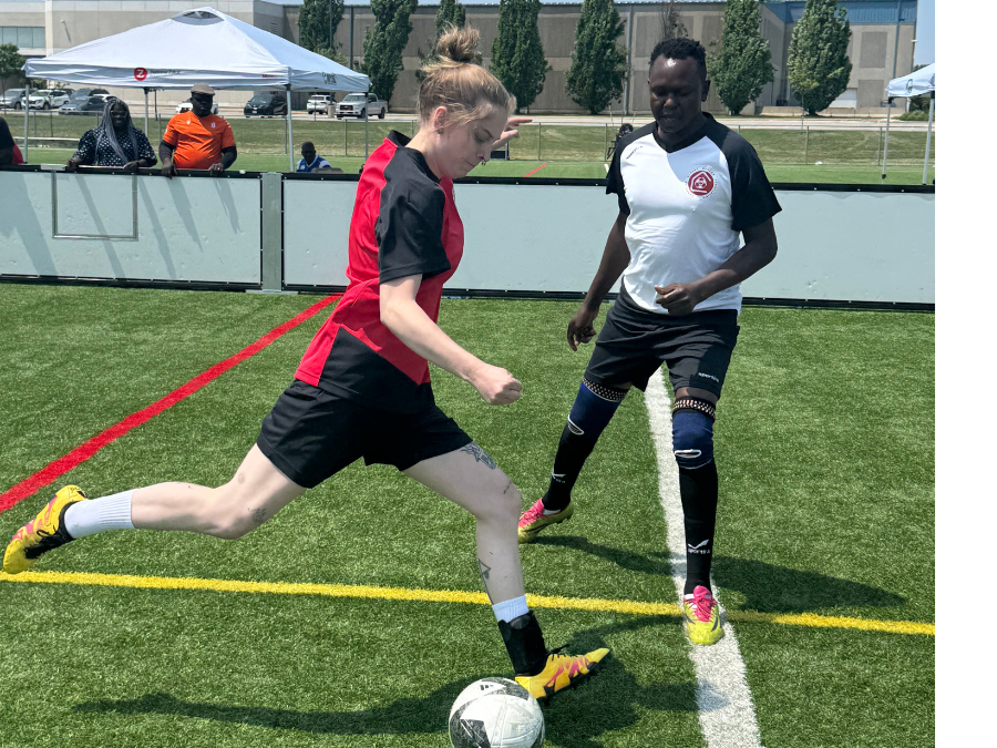 Emma Bellante, wearing a red and black jersey, kicks a soccer ball while a player in a white and black jersey defends during a match at the Canadian Street Soccer Association’s national tournament in Mississauga.