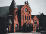 Gower Street United Church, a red-brick heritage building with green rooftops and a rose window, located in St. John’s, Newfoundland and Labrador, Canada.