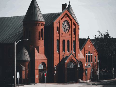 Gower Street United Church, a red-brick heritage building with green rooftops and a rose window, located in St. John’s, Newfoundland and Labrador, Canada.