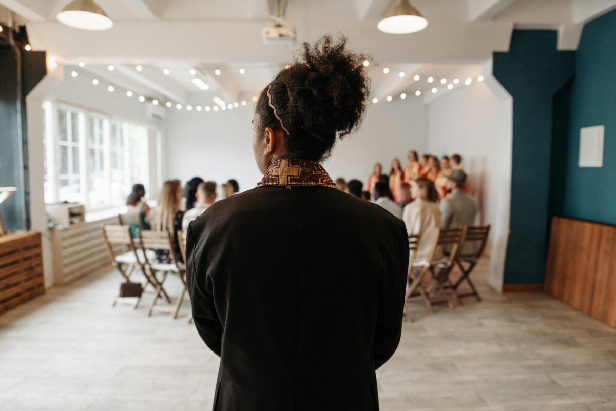 Back view of a pastor standing at a back of a choir practice in a church