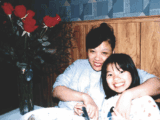 As Asian woman with black hair smiles and poses with an Asian child who has short black hair. She is also smiling