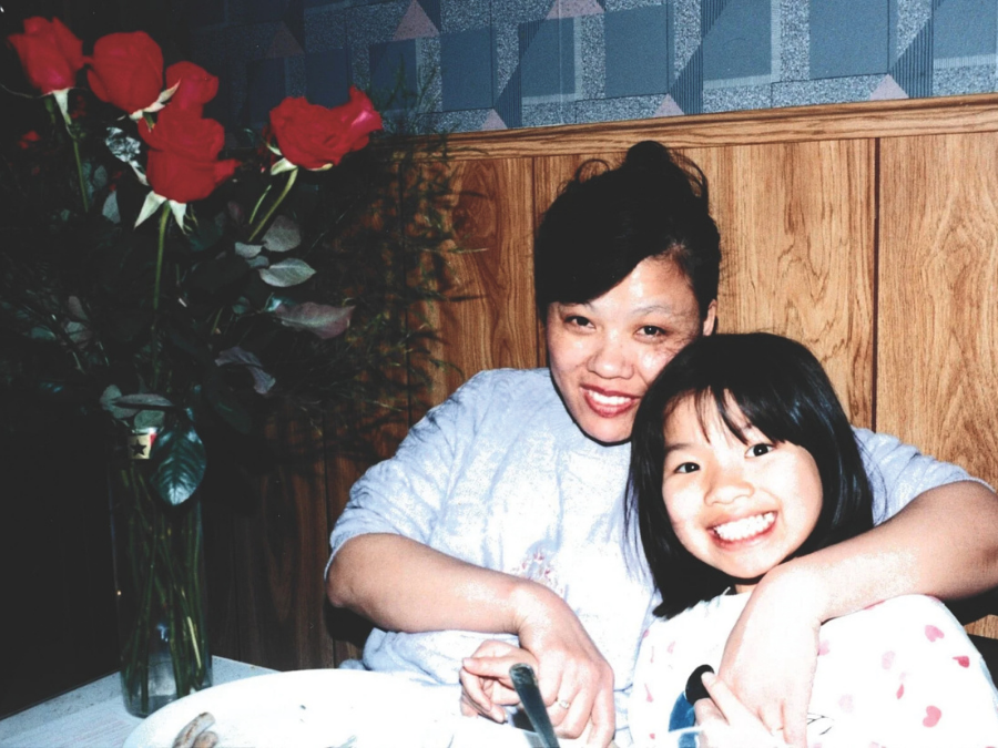 As Asian woman with black hair smiles and poses with an Asian child who has short black hair. She is also smiling