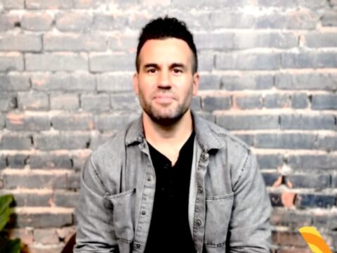 A Caucasian man sits in front of a camera