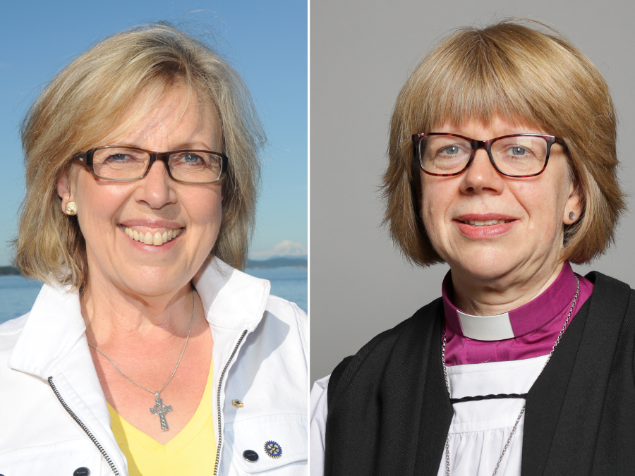 A woman with short blond hair and glasses wearing clerical attire, including a purple shirt, white collar, black vest, and cross necklace, looks at the camera.