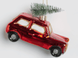 A red, glossy car-shaped ornament with a small green Christmas tree on top. The car has gold accents and black wheels, creating a festive tone.