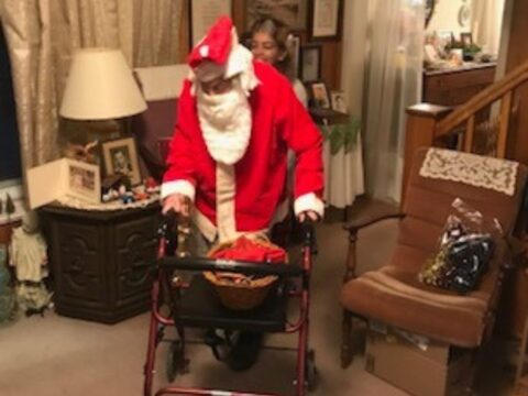 Santa, in bright red and white suit with a walker.