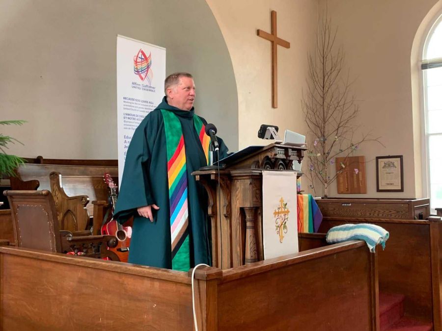 a Caucasian man in ministers' garb stands at pulpit in a church