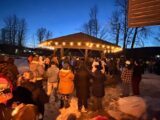 People stand holding candles near a gazebo