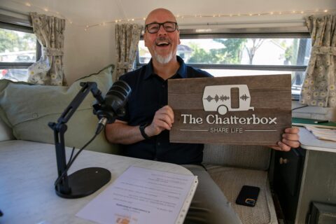 Man holding up sign saying The Chatterbox