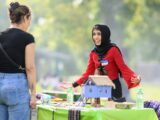 Volunteer Sadaf Saberi smiles as she explains some traditional Myanmar clothing and cultural objects at the Refugee Highway event